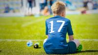 Young athlete sitting alone on the sidelines of an empty sports field